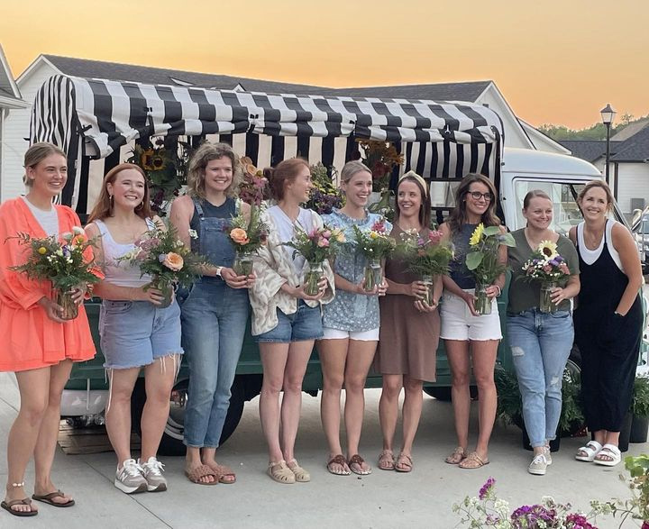 Flower event for friend group, nine women standing with flowers in front of Sallie the Flower Stem Bar Truck in Columbia, MO