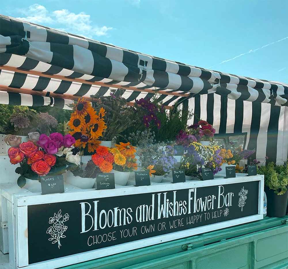 Sallie, the stem-bar truck, with the Blooms and Wishes sign and flowers on the truck for sale to make your own bouquet.