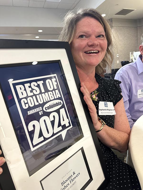 Blooms and Wishes owner Stephanie Whitman holds up the Best Florist of Columbia, MO 2024 award.